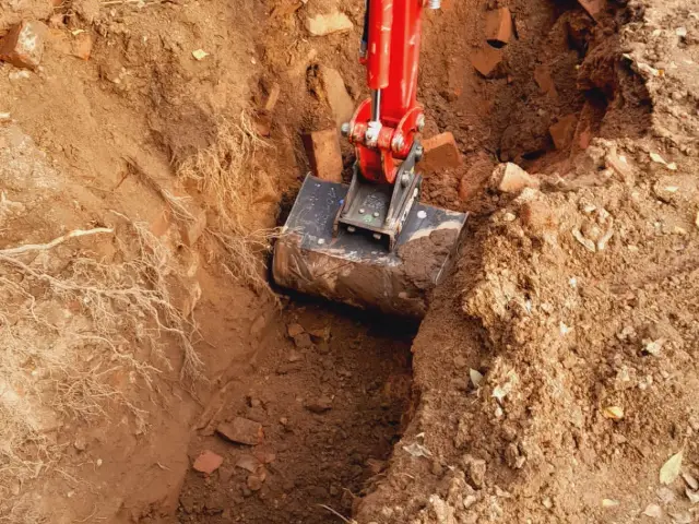 Baggerlöffel der Termin-Bau GmbH beim Ausheben eines Leitungsgrabens