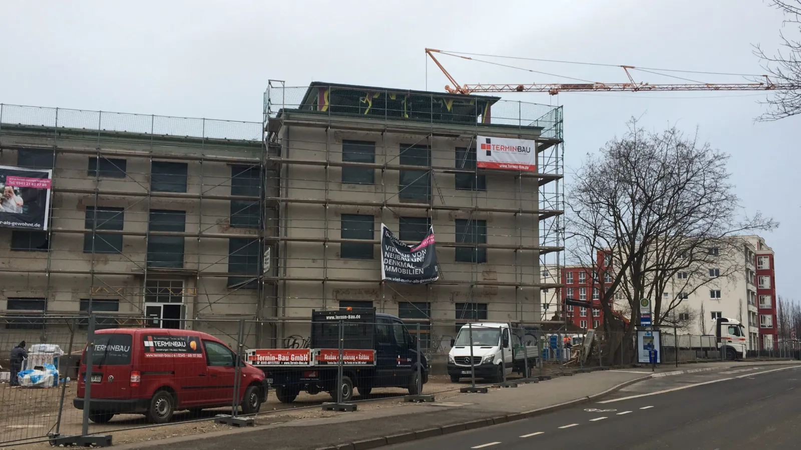 Eingerüstetes Bestandsgebäude während der Bauarbeiten mit Fahrzeugen der Termin Bau GmbH